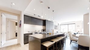 A modern kitchen with a central island, bar stools, and a dining area with a table and chairs. - Pool Deck, Hot Tubs & Gym - Stunning Condo in New Ski-In, Ski-Out Community (Park City)