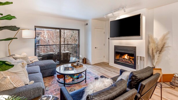 A modern living room with a fireplace, a large TV, and a balcony with a view. - Beautifully Updated Luxury Condo -Hot Tub - Walk to Town Lift (Park City)
