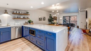 A modern kitchen with blue cabinets, a dishwasher, and a large island. - Beautifully Updated Luxury Condo -Hot Tub - Walk to Town Lift (Park City)