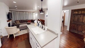 Een moderne keuken met een centraal eiland, een zithoek met een bank en een houten vloer.