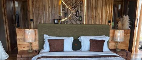 A large bed with a wooden headboard, two bedside tables with lamps, and a wooden floor.