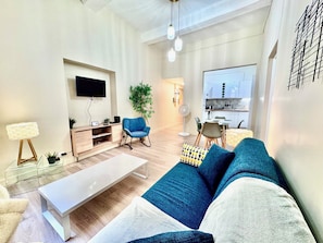 Een moderne woonkamer met een bank, salontafel, televisie en een eethoek met stoelen en een tafel.