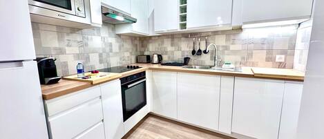 Una cocina moderna con armarios blancos, un microondas, un tostador y un lavabo.