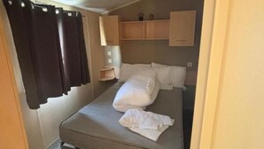 A compact room with a bed, a small bedside table, and a shelf above the bed. - Seaside Tranquility Retreat in Clacton (Clacton-on-Sea)