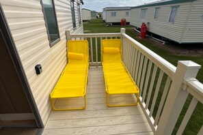 A deck with two yellow lounge chairs and a white railing. - Seaside Tranquility Retreat in Clacton (Clacton-on-Sea)