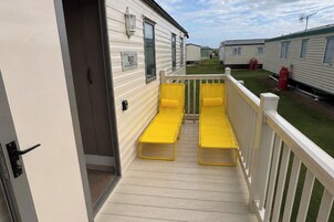 Una terraza con dos sillones amarillos y una baranda blanca.