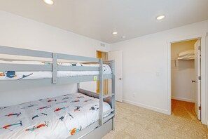Ein Schlafraum mit Etagenbetten, einem Kleiderschrank und einer Tür zu einem weiteren Zimmer.