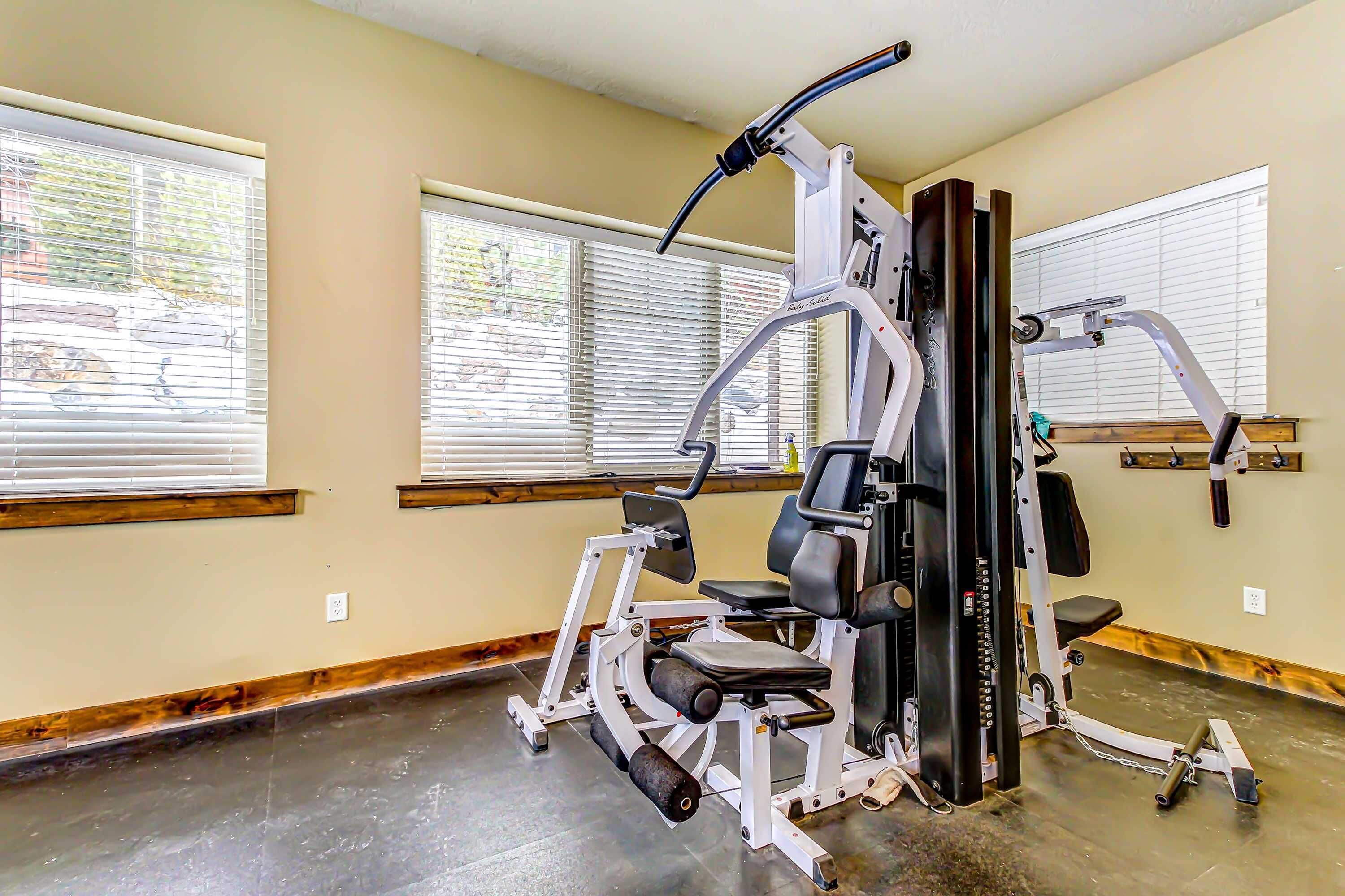 Ein Fitnessstudio mit Trainingsgeräten, großen Fenstern und Holzboden.