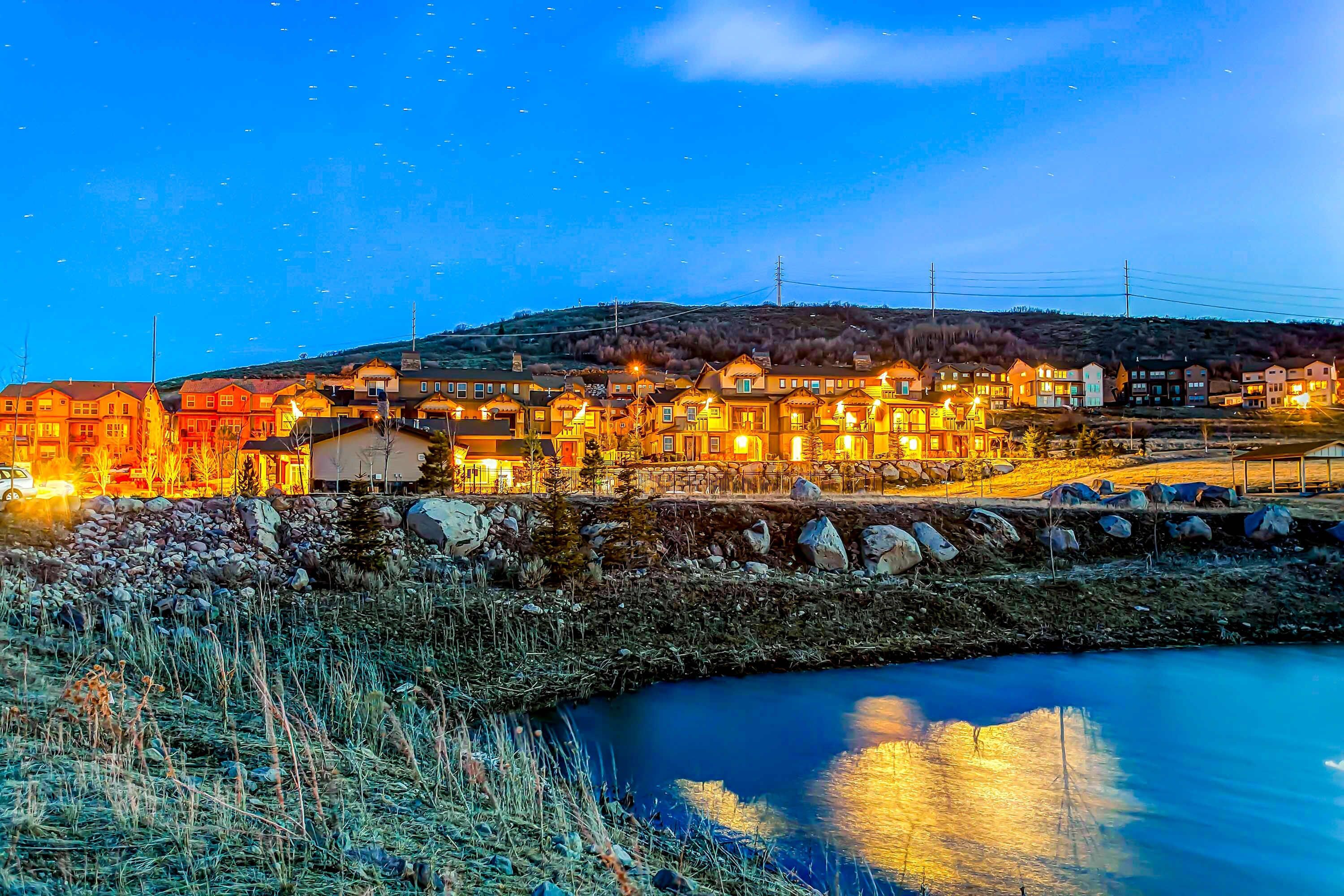 Un pueblo con edificios a lo largo de la orilla de un río, un muro de piedra y un cielo nocturno despejado.