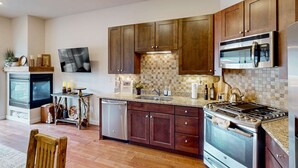 A modern kitchen with wooden cabinets, a stainless steel stove, a microwave, and a dishwasher. - Inviting condo in Newpark Town Center with hot tub and great balcony views (Park City)