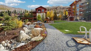 A lodge with a red and brown exterior, a gravel path, and a well-maintained lawn. - Mountainview Condo with Ski-In/Out Access, Club Solitude Access with Pool & Hot Tub (Solitude)