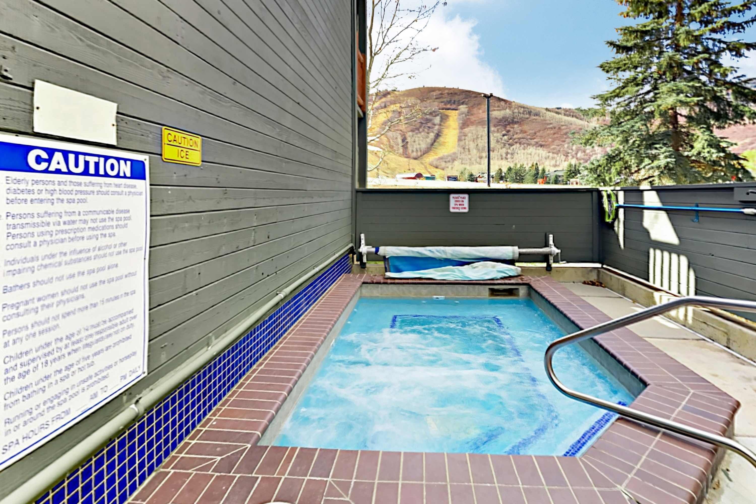 A spa area with a caution sign, a pool, and a view of a mountain.