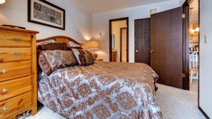 Een slaapkamer met een bed, een kaptafel, een lamp en een lijst met een afbeelding aan de muur.