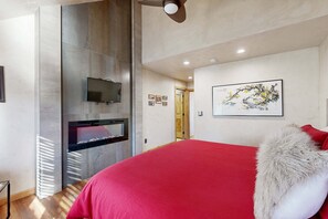 Une chambre avec un grand lit, un téléviseur fixé au mur et un tableau accroché au mur.