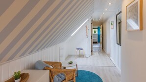 Ett rum med ett sluttande tak, en matplats med bord och stolar och en hall som leder till ett annat rum.