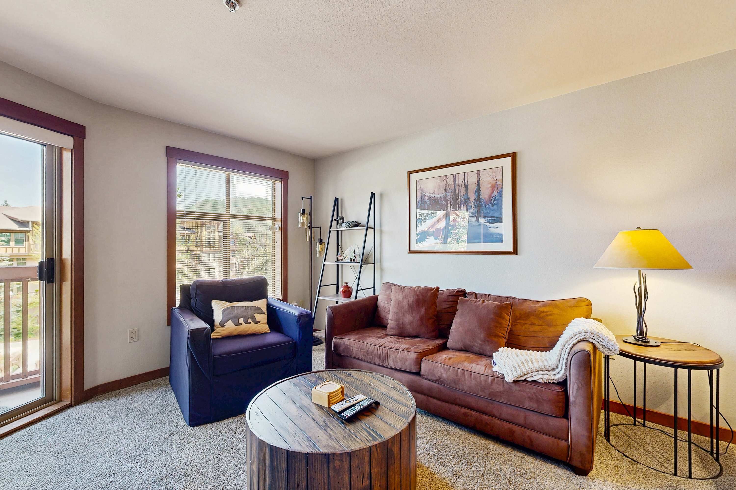 A living room with a brown sofa, a blue armchair, a round coffee table, and a lamp.