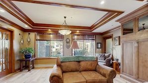 Un soggiorno con un divano marrone, soffitto in legno e ampie finestre.
