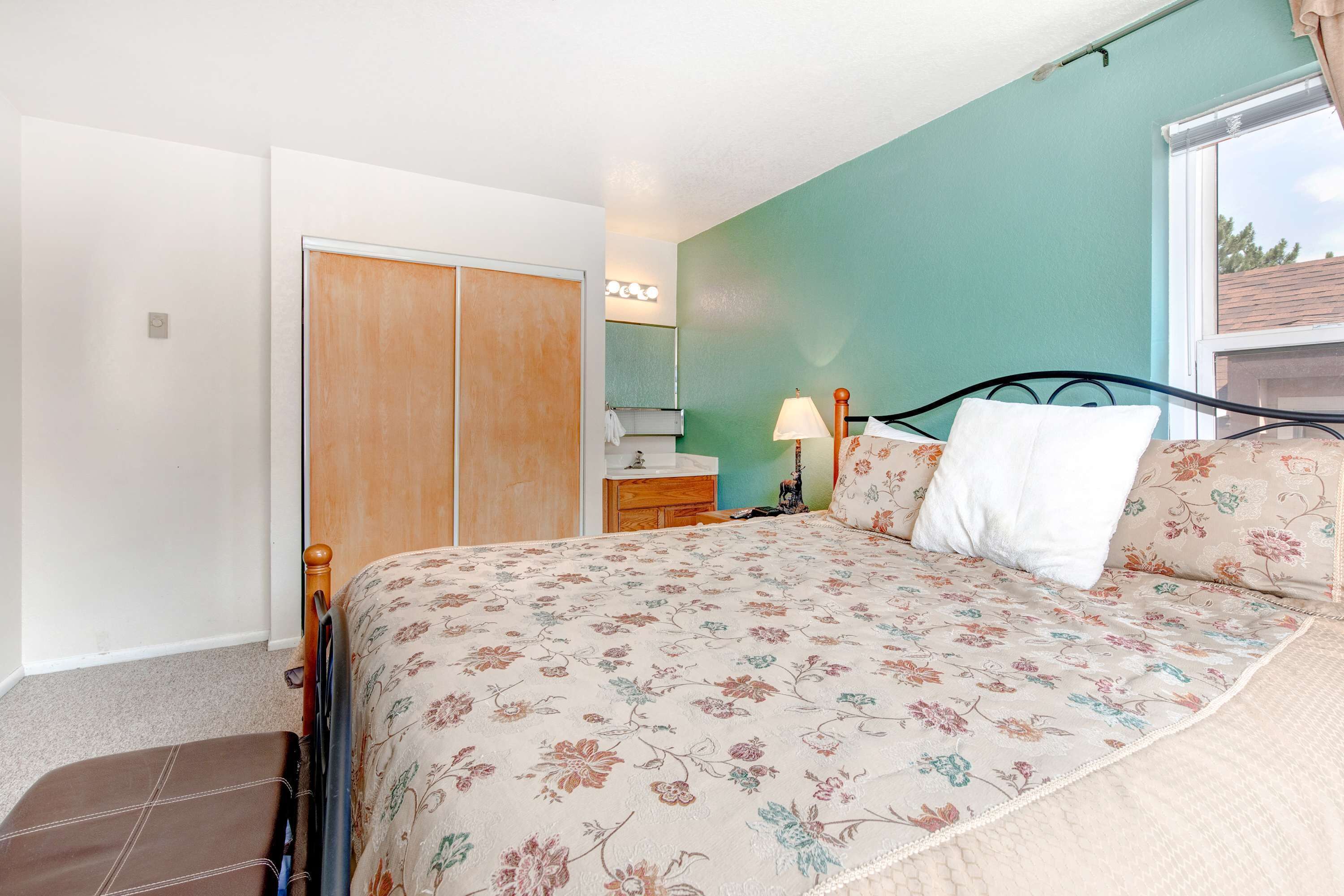 Un dormitorio con cama, cómoda, espejo y ventana.