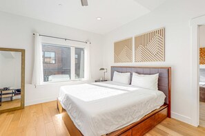 Ein modernes Schlafzimmer mit einem großen Bett, einem Fenster, einem Spiegel und einer Wanddekoration.
