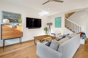 A living room with a sofa, a coffee table, a TV, a wooden cabinet, a globe, and a staircase. - Luxurious, dog-friendly home with  private hot tub, W&D, AC, WiFi, near slopes (Park City)