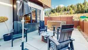 Une terrasse avec mobilier d’extérieur, une plateforme en bois et une vue sur une zone boisée.