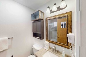 Ein Badezimmer mit Waschbecken, Spiegel, Toilette, Handtuchhalter und einem Spiegel mit Holzrahmen.