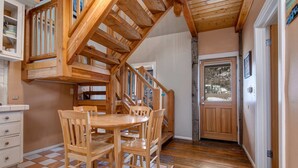 A wooden staircase leading to a second floor, a dining area with a wooden table and chairs, and a door with a view of the outside. - Quintessential Historic Old Town-Full Kitchen-Mountain Views (Park City)