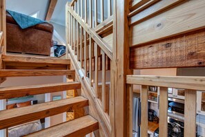Eine Holztreppe mit Blick auf einen Küchenbereich darunter.