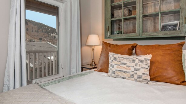 A bedroom with a bed, a window, a lamp, and a cabinet. - Quintessential Historic Old Town-Full Kitchen-Mountain Views (Park City)