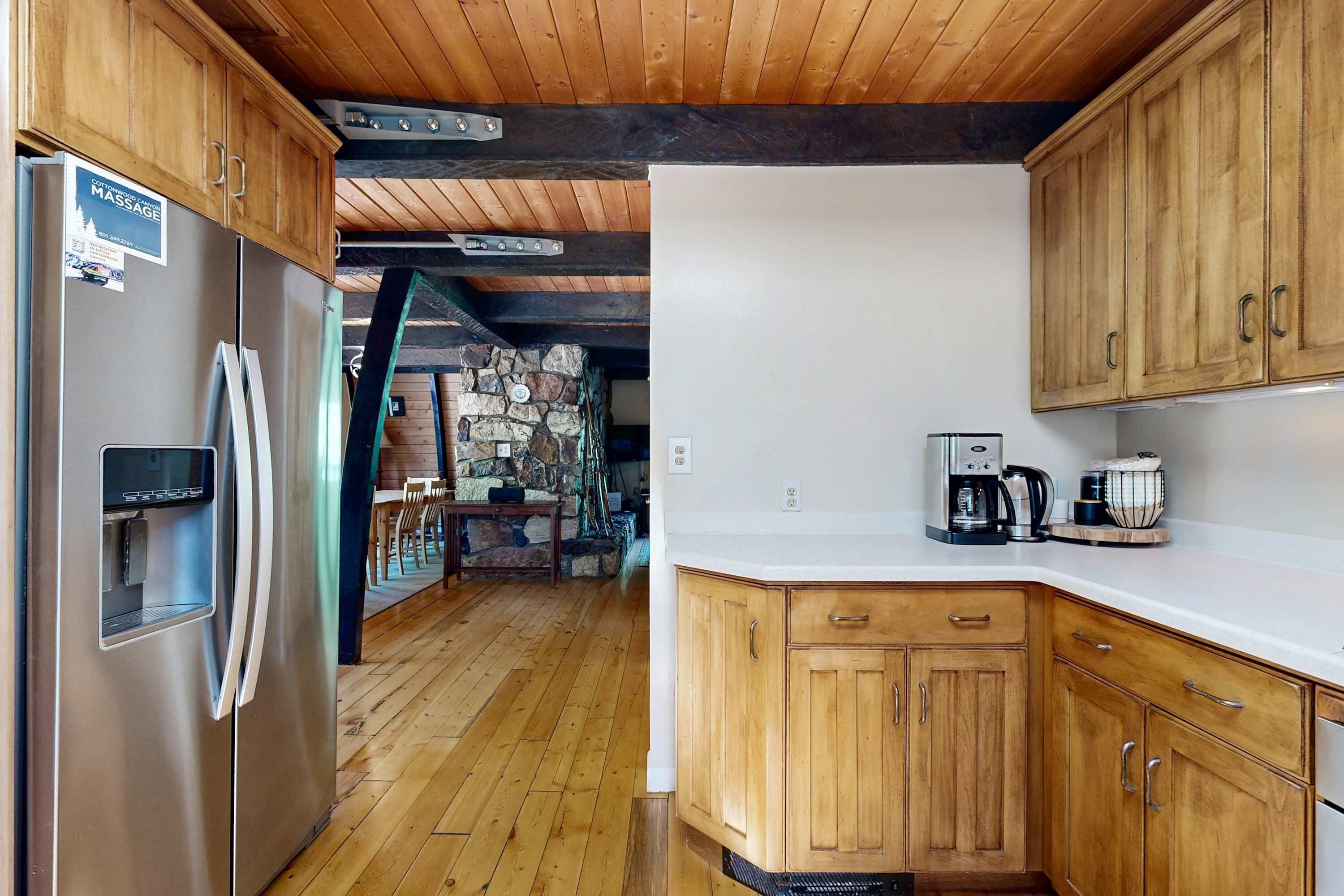Una cocina con armarios de madera, un refrigerador de acero inoxidable y una cafetera sobre la encimera.