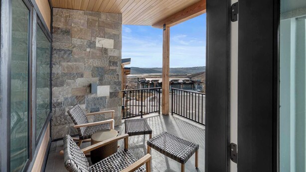 A balcony with stone walls, wooden ceiling, and a view of a distant landscape. - Panoramic views, hot tub & game room, Minutes from Jordanelle Express Gondola (Heber City)