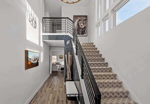 Eine Treppe mit gemustertem Teppich, einem schwarzen Geländer und einem Bärenbild an der Wand.