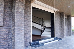 A modern building entrance with a stone facade, a staircase with metal railings, and a flat roof. - Deluxe Hotel Dhaba (Nagpur)