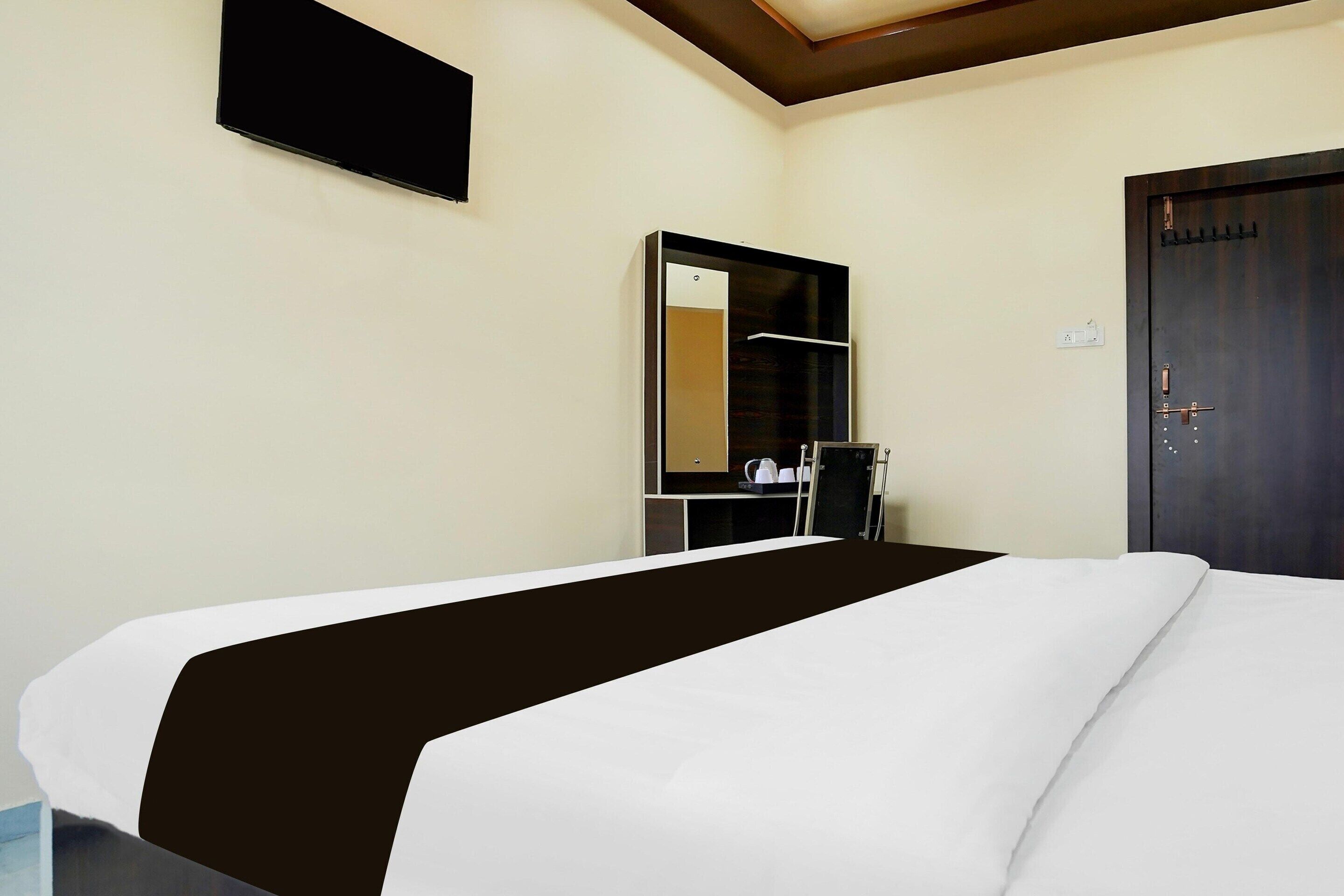 A hotel room with a bed, a wardrobe, a mirror, and a door.