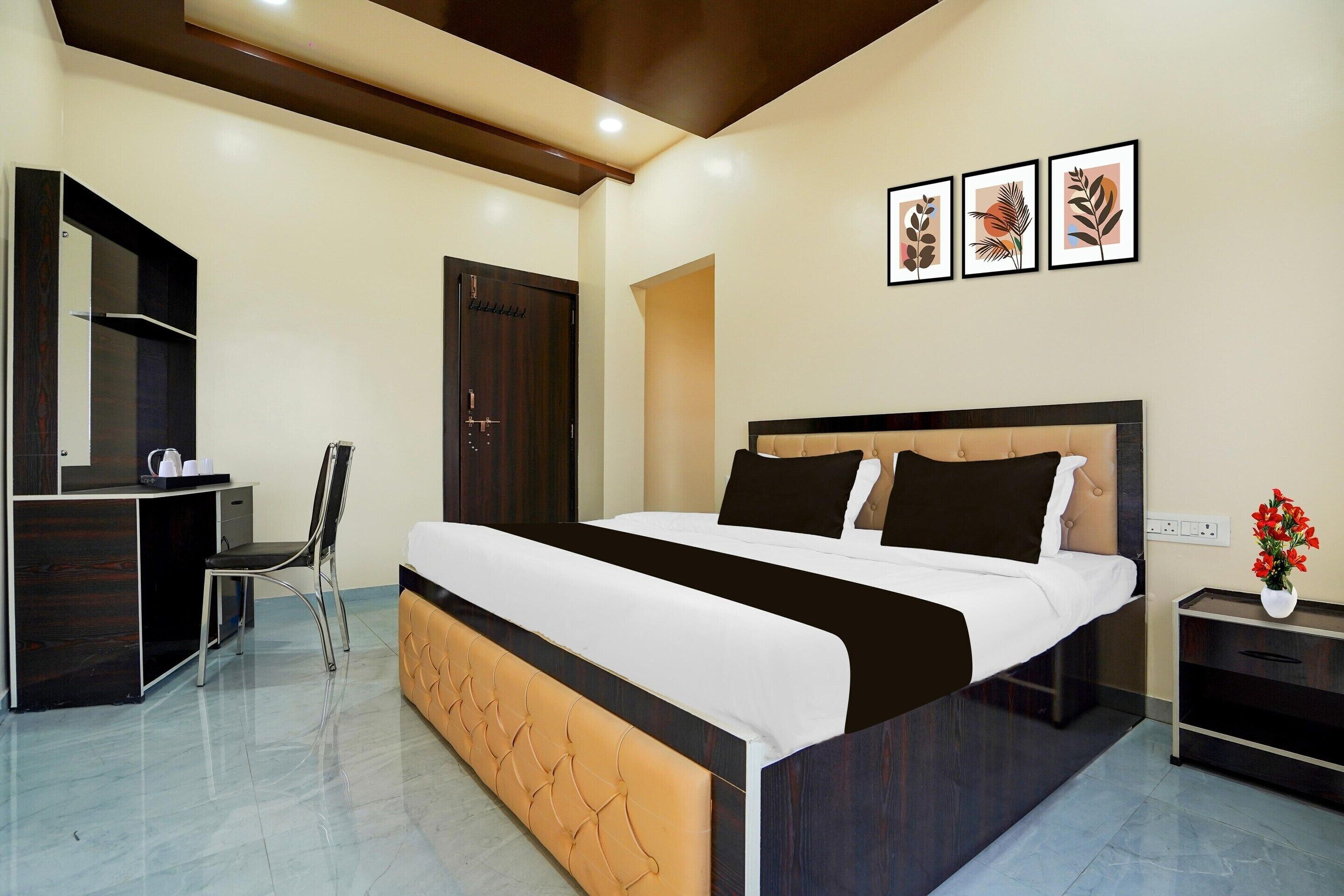 A modern bedroom with a bed, desk, chair, and a nightstand with a vase of flowers.