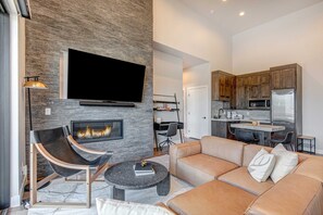 A modern living room with a fireplace, a flat-screen TV, and a sofa. - Stunning Views, Family Fun & Steps from Deer Valley's New East Village (Hideout)