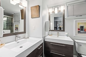 A modern bathroom with two sinks, a large mirror, and a toilet. - Stylish condo in prime location just steps from Main Street & Town Lift Plaza (Park City)