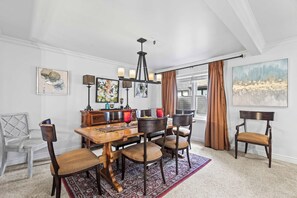 A dining area with a wooden table, chairs, a chandelier, and artwork on the walls. - Stylish condo in prime location just steps from Main Street & Town Lift Plaza (Park City)