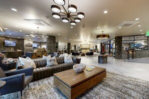 A modern lobby with a leather sofa, a wooden coffee table, and a stone accent wall. - Modern resort condo with pool, hot tub, rolling foothill views & shuttle (Heber City)