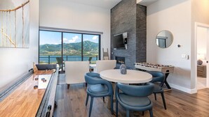 Ein modernes Wohnzimmer mit Kicker, Kamin und großem Fenster mit schöner Aussicht.