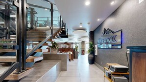 Un hall d’hôtel moderne avec un escalier, un comptoir d’accueil et un panneau indiquant le « Restaurant Overlook ».