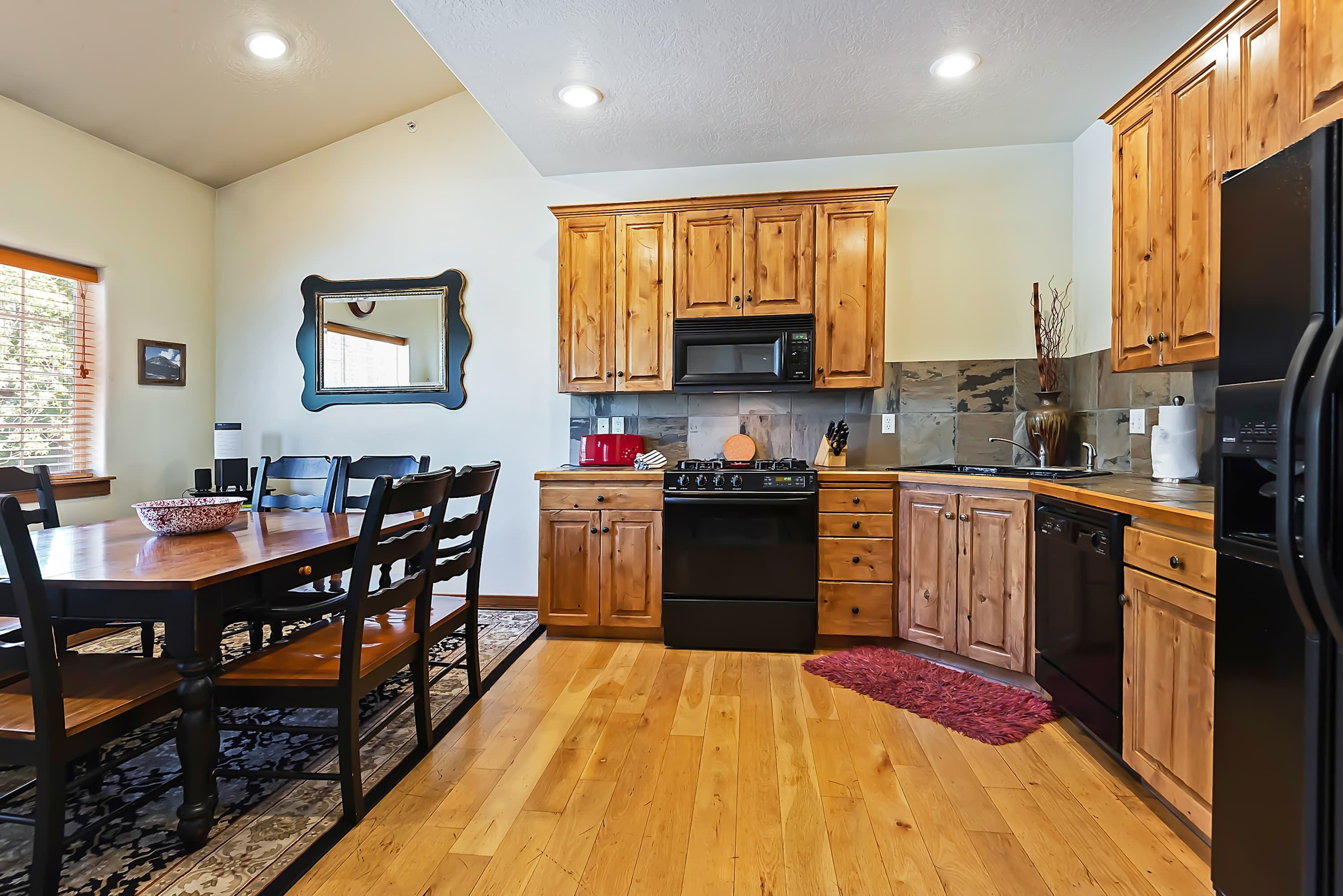 A kitchen with wooden cabinets, a microwave, stove, and dishwasher.