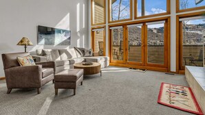 Ein geräumiges Wohnzimmer mit großem Fenster, einer Couch, einem Couchtisch und einem Teppich.