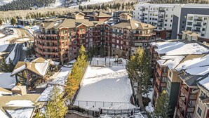 A multi-story hotel with a ski slope in the foreground, surrounded by snow-covered mountains. - ski-in ski-out Condo with Shared Hot Tubs & Pool, High-Speed WiFi, and Central AC (Park City)