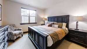 Un dormitorio con una cama grande, un aparador, una silla y una ventana.