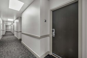 A hallway with a carpeted floor, white walls, and a door with a handle. - Central condo with WiFi, AC, patio, hot tub, & seasonal pool (Park City)