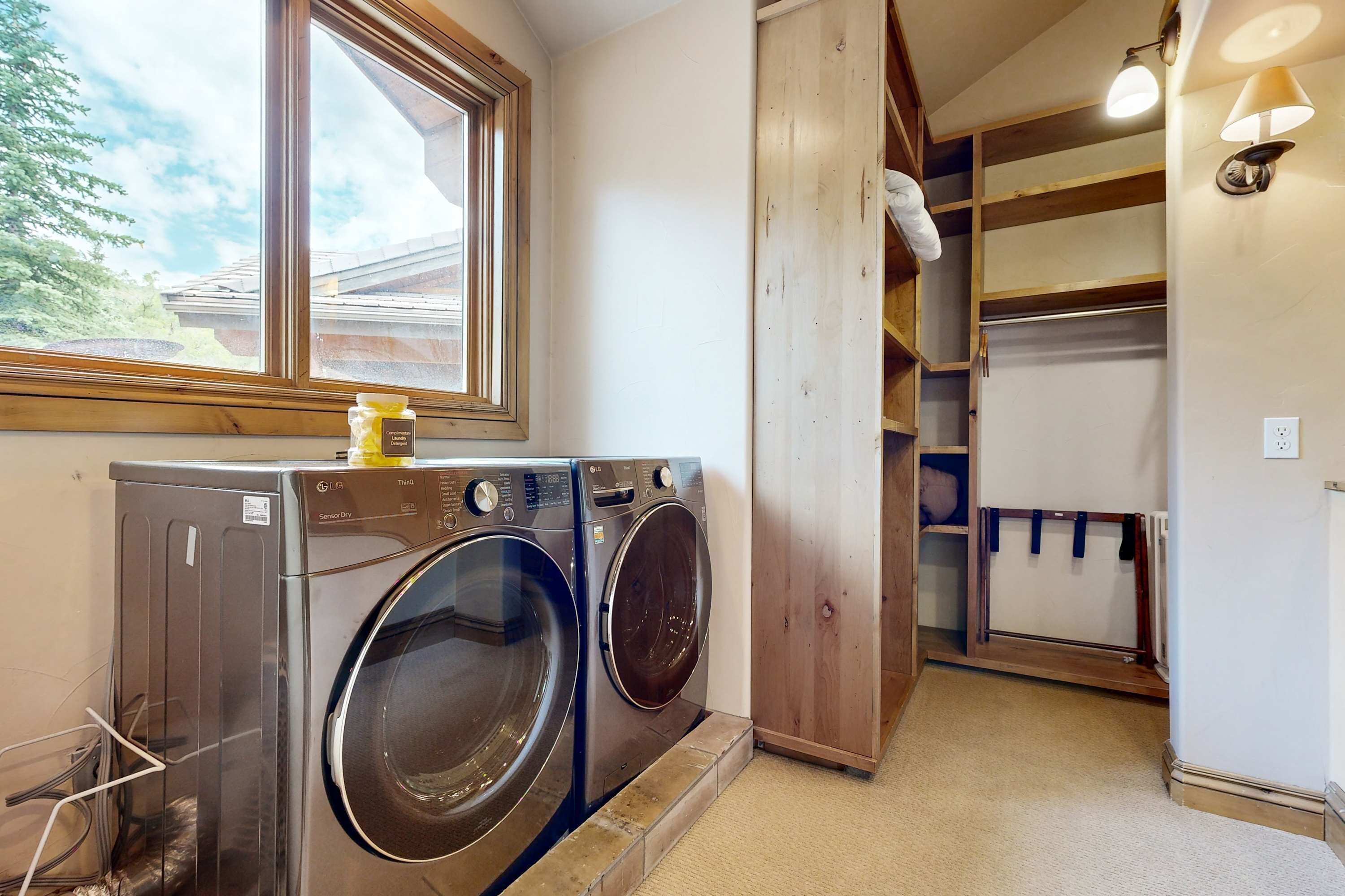 Un área de lavandería con dos lavadoras, una ventana y un estante de madera.