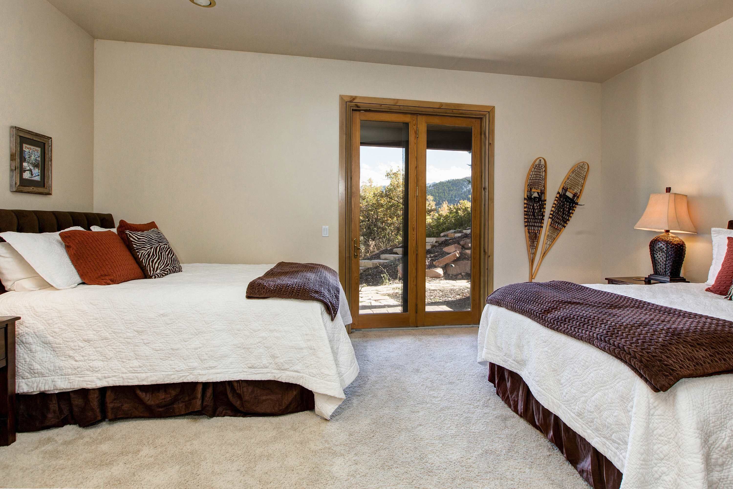 A bedroom with two beds, a sliding glass door to a patio, and a framed picture on the wall.