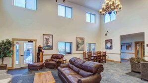 Eine geräumige Lobby mit Ledersofas, einem Holztisch und einem Kronleuchter.