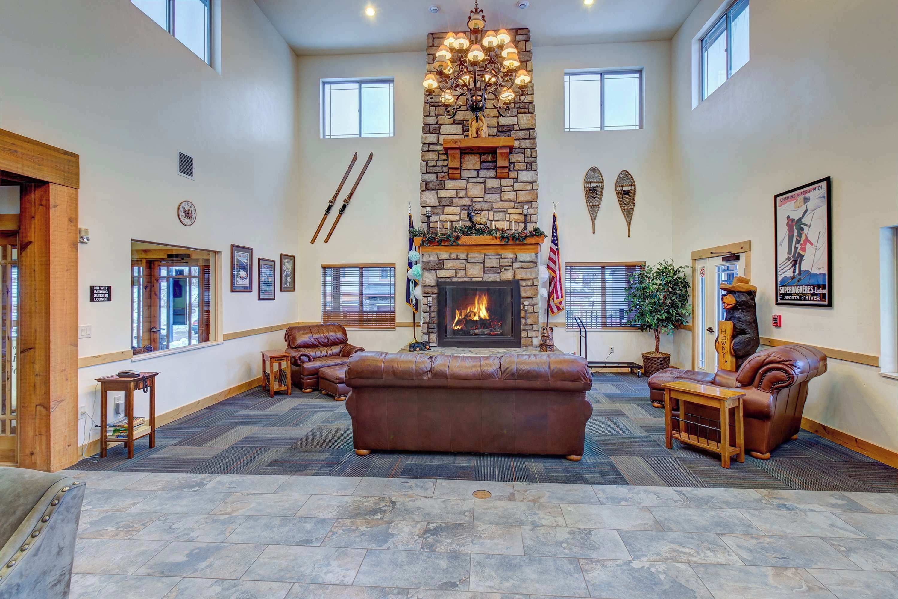 A spacious lobby with a stone fireplace, leather sofas, and a chandelier.